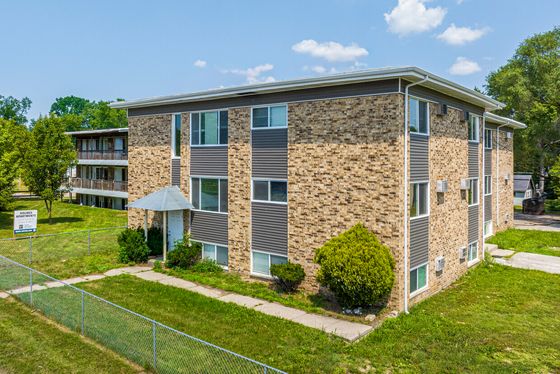 Charming brick apartment complex with lush greenery, showcasing modern living with ample natural light.