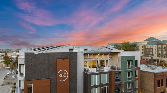 Vibrant apartment building with modern architectural design against a stunning sunset sky.
