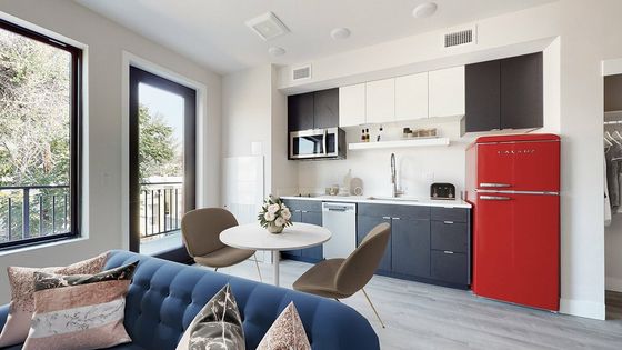 Contemporary apartment kitchen with a vibrant red fridge, stylish seating area, and expansive windows.