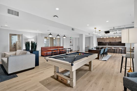 Modern communal space featuring a cozy lounge area, stylish pool table, and a sleek dining area, perfect for social gatherings.