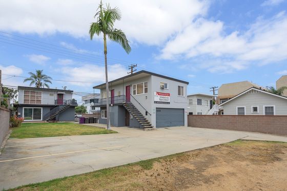 Inviting apartment complex exterior featuring well-maintained landscaping and ample parking under a clear blue sky.