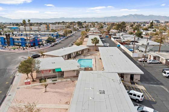 Charming aerial view of a residential complex featuring a central swimming pool, scenic mountain backdrop, and vibrant surrounding neighborhood.