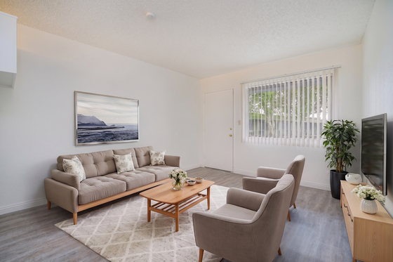 Bright and inviting living room with modern beige furniture, elegant wooden coffee table, and large window with vertical blinds.