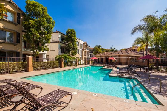 Large sparkling community pool surrounded by lounge chairs and umbrellas for resident relaxation.