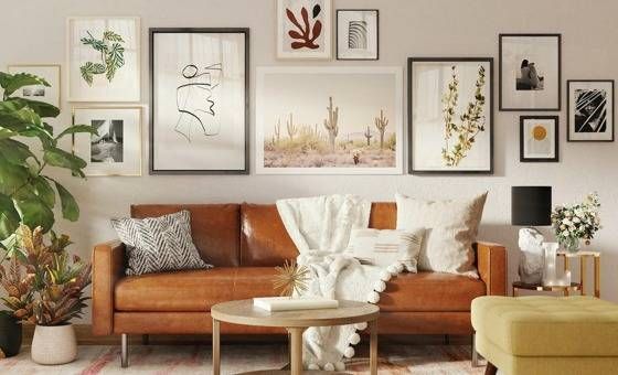 brown leather sofa with many art frames hanging behind