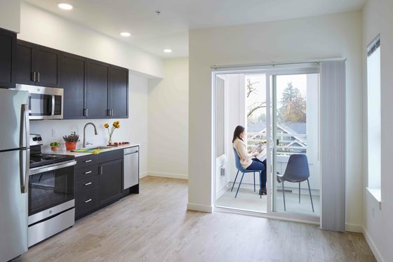 open kitchen and dining area with woman sitting in a blue chair outside in the patio reading a book at 330 dekum