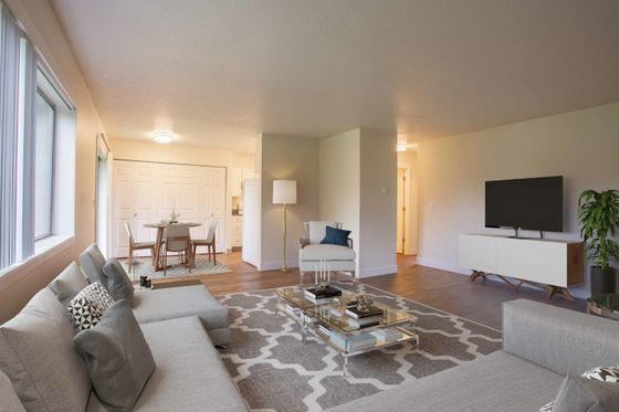 staged living room with taupe sectional entertainment console with tv and a dining table in the dining area