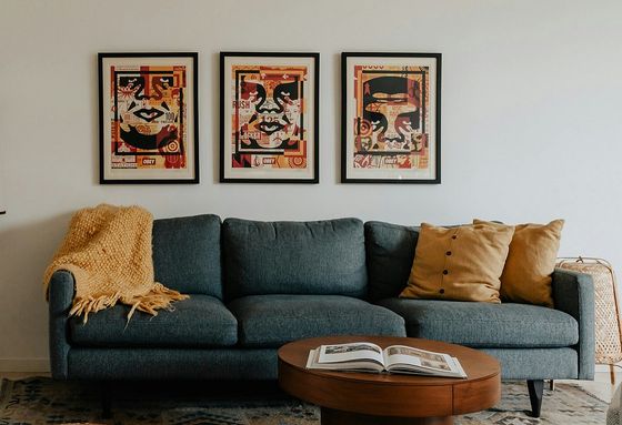 blue sofa with yellow accent pillows and yellow trow and round coffee table with open book