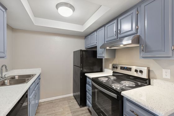Kitchen at Solaris at Shadow Mountain with blue cabinetry, white counters, and black appliances.