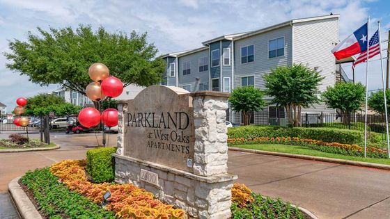 Entrance sign with balloons, flags and three-story buildings, Houston, TX