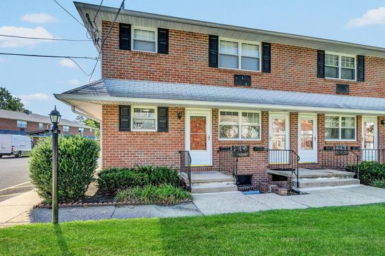 Charming brick townhouse exterior with classic black shutters and a well-kept front garden, perfect for a cozy suburban lifestyle.