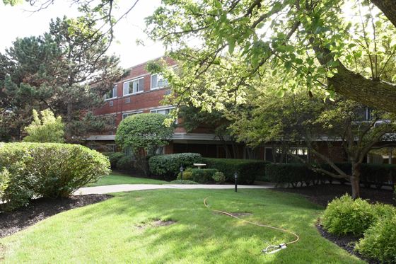Garden House a seventy unit mid century two story red brick property with mature trees and lush landscaping in Skokie from a side perspective.