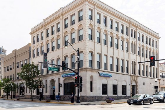 A four story white brick apartment building with a Fifth Third Bank branch on first floor.