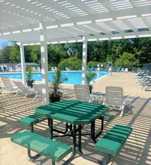 Inviting outdoor area featuring a serene swimming pool, elegant white pergola, and comfortable seating, perfect for relaxing and enjoying sunny days.