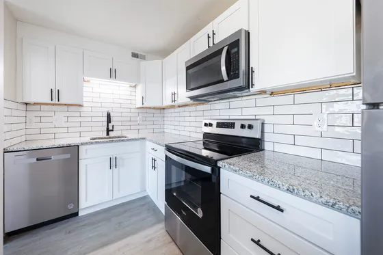 Sleek kitchen with modern appliances, white cabinets, and granite countertops.