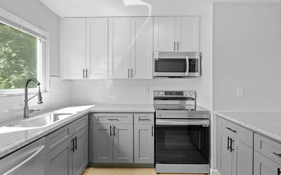 Modern kitchen with sleek grey cabinets, stainless steel appliances, and ample natural light from a large window.