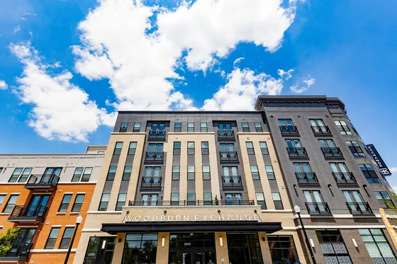 Chic urban apartment building with modern design and large windows under a clear blue sky.