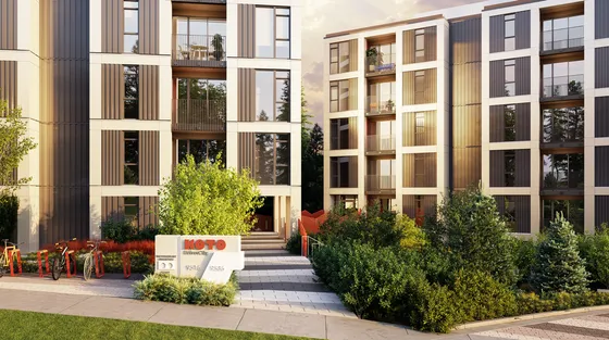 Modern apartment complex with stylish facade, lush greenery, and bike-friendly amenities at sunset.