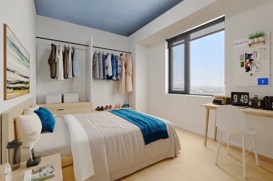 Bright and modern bedroom featuring stylish closet space, cozy bed with blue accents, large window offering natural light, and a functional desk area for productivity.