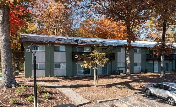 Charming apartment complex with a lush autumn landscape, offering a serene living experience surrounded by vibrant fall foliage.