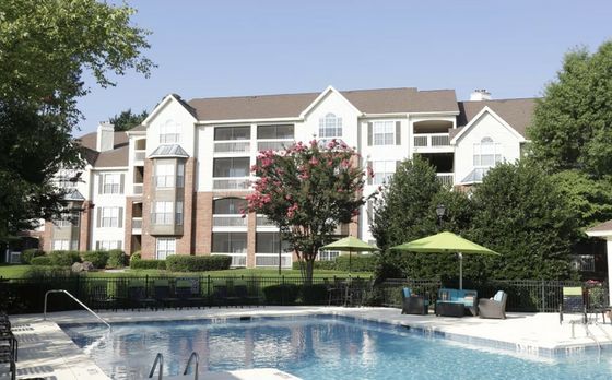 Charming residential apartment complex with lush greenery, vibrant landscaping, and a sparkling outdoor pool for relaxation.
