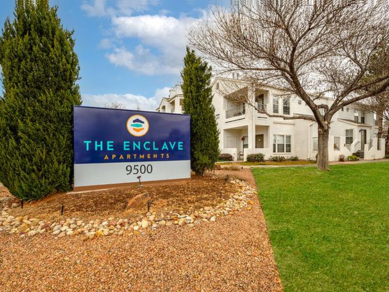 Charming view of The Enclave Apartments with lush green lawn and elegant architecture.