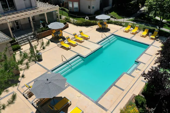 Inviting outdoor pool area with vibrant yellow sun loungers and stylish umbrellas, perfect for relaxation and entertainment.