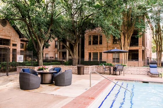 Inviting apartment complex with a sparkling pool, stylish outdoor seating, and lush greenery, perfect for relaxation and social gatherings.
