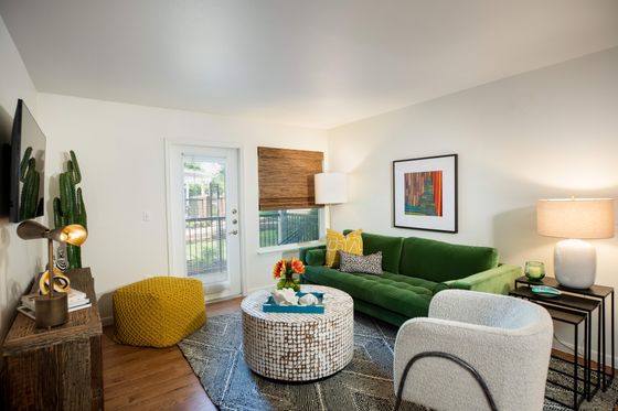 Chic and inviting living room with a vibrant green sofa, cozy seating, and modern decor in a well-lit space opening to a scenic patio.