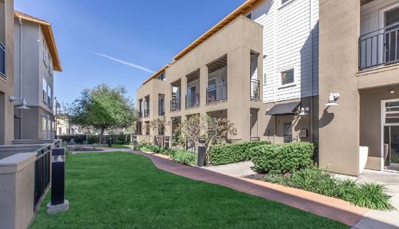 Modern apartment complex with green lawn and balconies, featuring contemporary architecture.