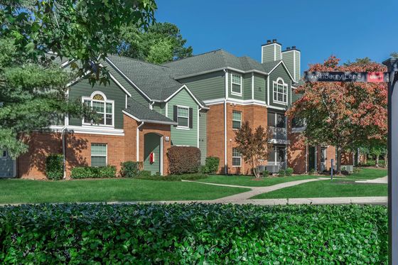 The Ashberry Apartments Green and Brick Building Exterior with Lush Landscaping