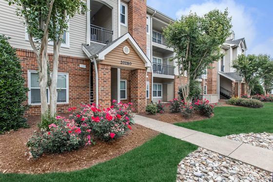 The Brixton at Loudoun Apartments Building Exterior with Lush Landscaping and Red Flowers