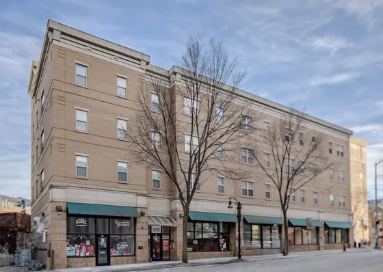 Charming urban apartment building with modern amenities, spacious windows, and convenient street-level shops.