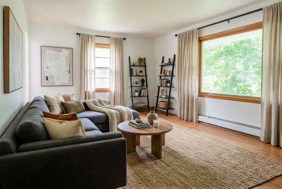 Inviting living room with a cozy gray sectional sofa, stylish wooden coffee table, and abundant natural light filtering through large windows.
