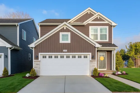 Charming modern house with a cozy front porch, vibrant landscaping, and a spacious two-car garage.