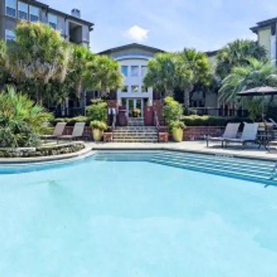 NXNW, exterior, sparkling blue swimming pool, large building, trees, lounge chairs