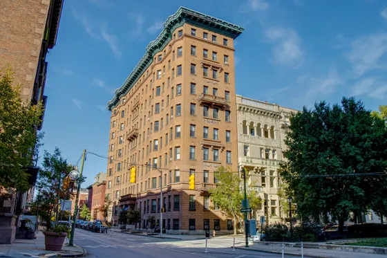 Elegant urban apartment building with classical architecture, offering city living with modern amenities, framed by a vibrant street view.