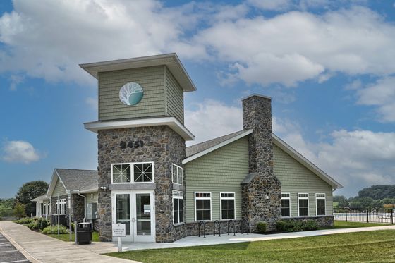Elegant stone clubhouse with modern architecture surrounded by lush greenery under a bright blue sky.