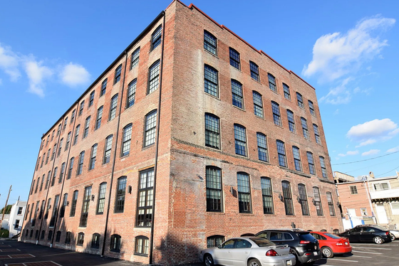Charming historic brick building with large windows and ample parking, perfect for urban living.