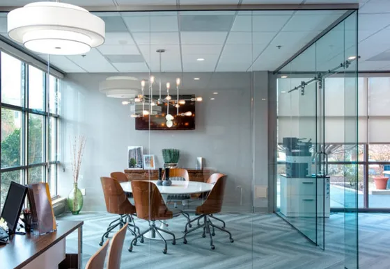 Modern office space featuring a sleek glass-walled conference room with stylish lighting and comfortable seating.