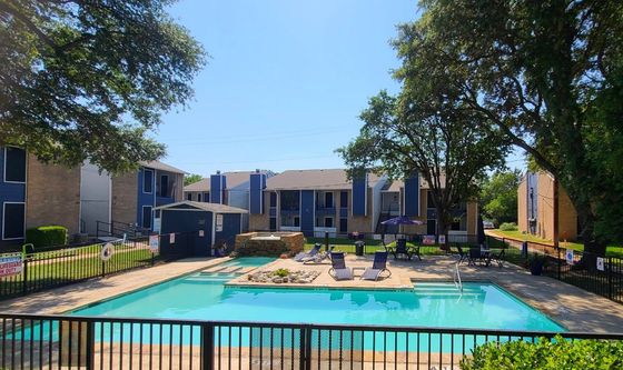 Inviting apartment complex with a sparkling pool, surrounded by lush greenery and modern architecture, perfect for relaxation and leisure.