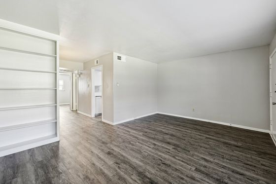 Spacious living area with sleek hardwood floors and built-in shelving, perfect for modern decor.