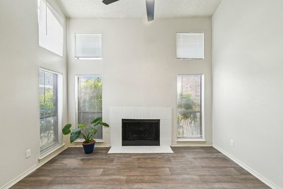 Bright living room featuring tall ceilings, large windows, a modern fireplace, and elegant wood flooring.