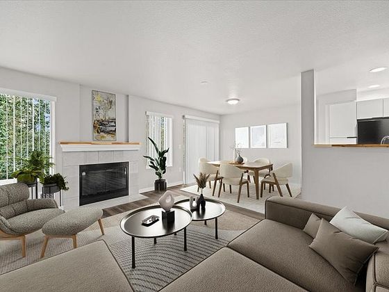 Bright and inviting living area with modern furniture, a cozy fireplace, dining space, and open kitchen layout.