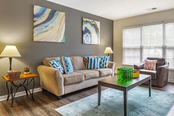 Centennial Ridge living room with a plush beige sofa, vibrant blue pillows, abstract wall art, and natural light, located in Raleigh, NC