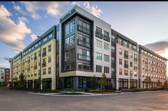 Modern urban apartment building with large windows and sleek design at sunset.