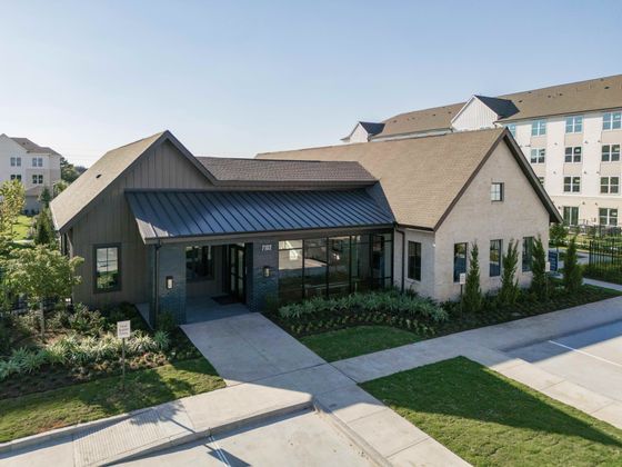 Charming residential building with modern design and lush landscaping, bathed in natural sunlight.