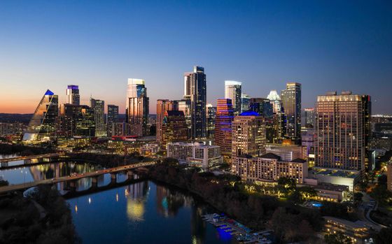Breathtaking cityscape at dusk featuring illuminated high-rises reflecting on a tranquil river, ideal for vibrant urban living.