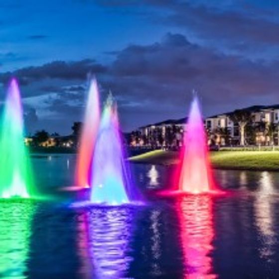 The Reserve at Coral Springs, exterior, night, rainbow fountains in pond, buildings
