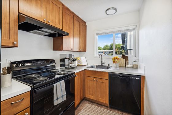 Cozy kitchen with wooden cabinets, black appliances, and a window view.